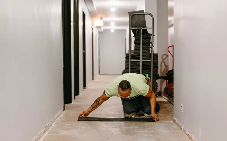Construction worker laying flooring for multifamily renovation project.